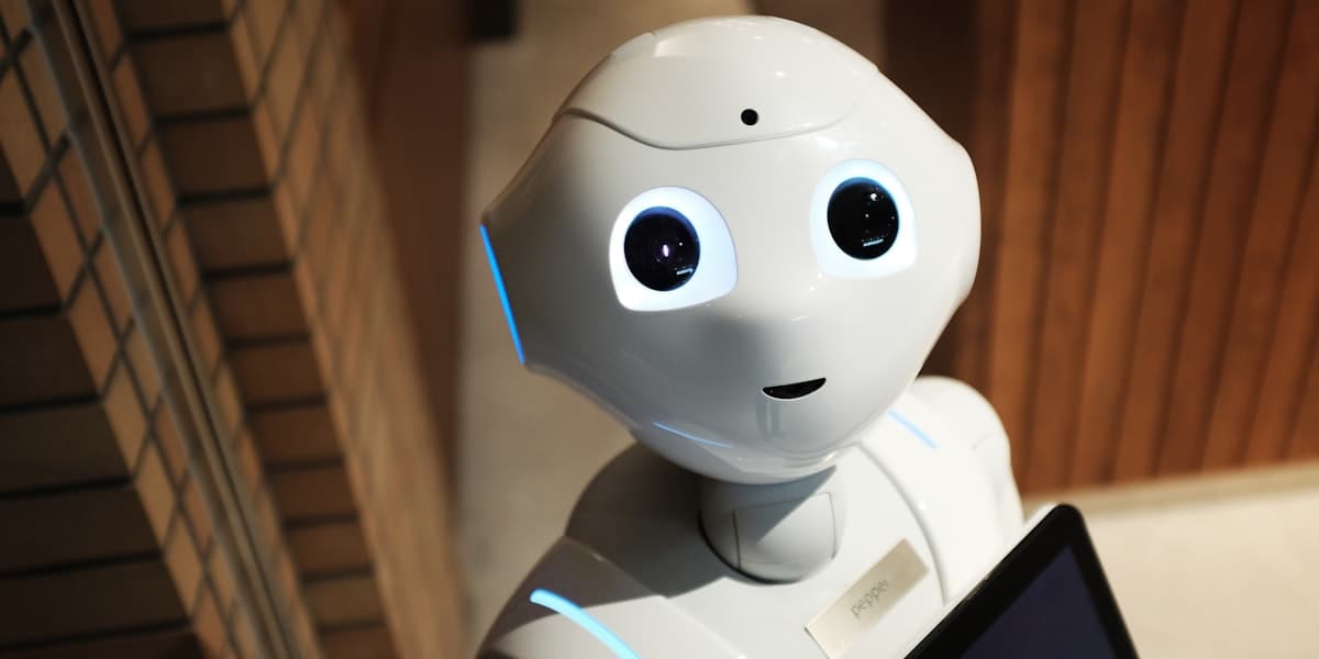 Close-up of a white humanoid robot with illuminated eyes, representing AI-powered robotics