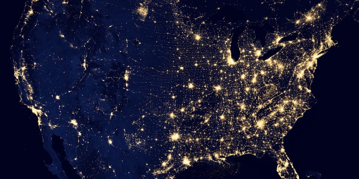 Satellite night-time view of illuminated city lights and infrastructure networks across the United States